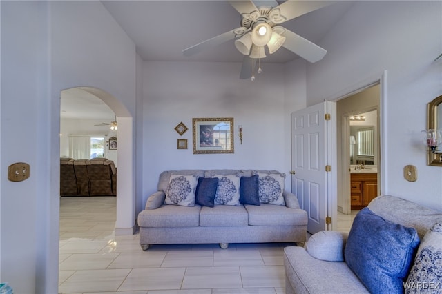 living room with a ceiling fan and arched walkways