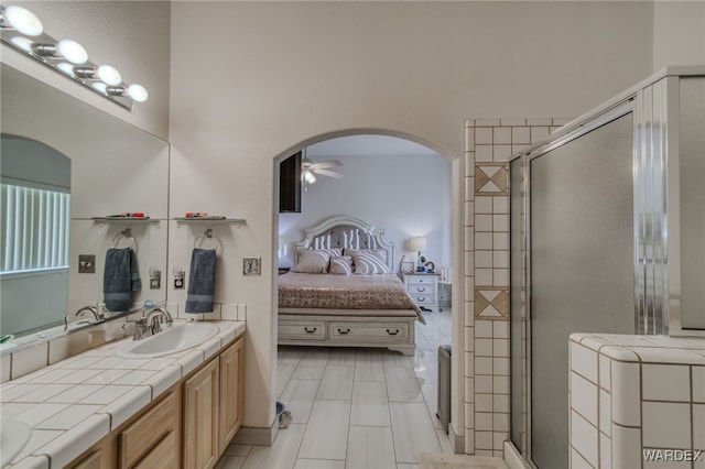 ensuite bathroom with ensuite bathroom, a sink, ceiling fan, double vanity, and a stall shower