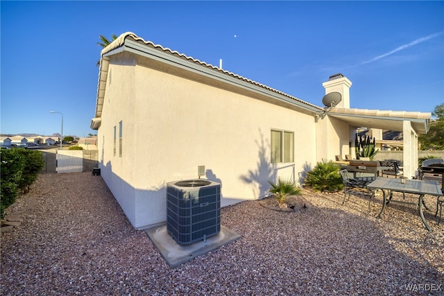 rear view of house featuring a patio area, stucco siding, and central air condition unit