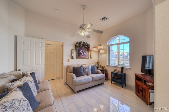 living area featuring visible vents, a wood stove, a ceiling fan, and lofted ceiling