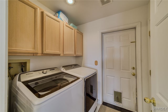laundry area featuring washing machine and dryer, visible vents, and cabinet space