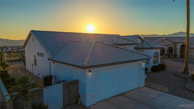 view of front facade featuring stucco siding, a mountain view, driveway, an attached garage, and a tile roof