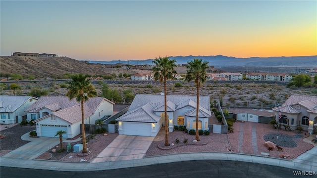 aerial view at dusk featuring a mountain view and a residential view