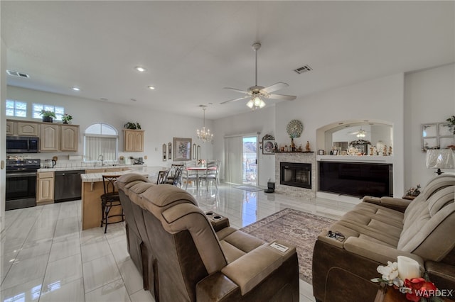living room featuring visible vents, a wealth of natural light, and ceiling fan with notable chandelier