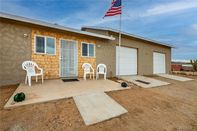 rear view of property with a garage and stucco siding