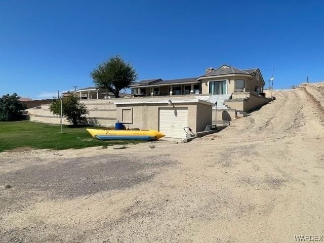 rear view of house featuring stucco siding, a yard, and driveway
