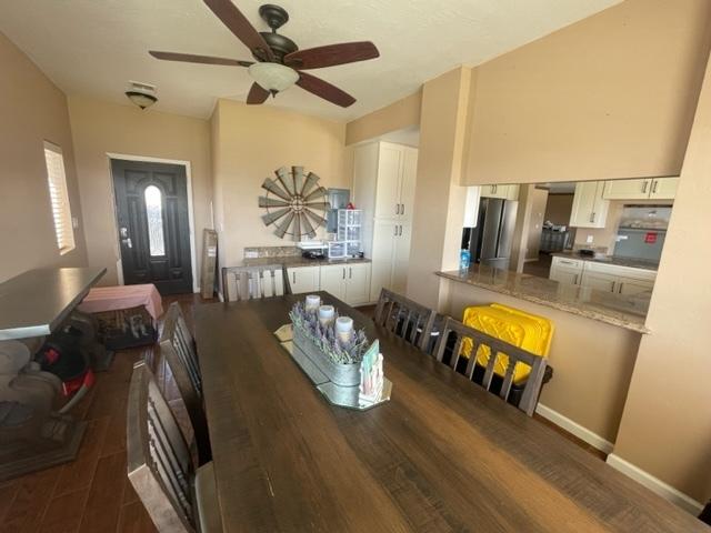dining space with ceiling fan, wood finished floors, and baseboards