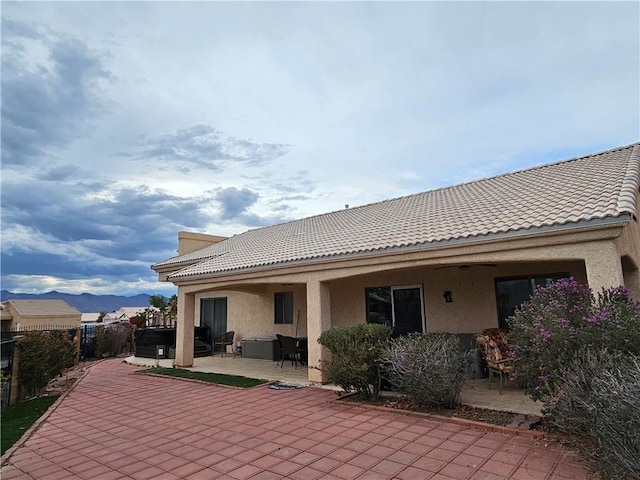 2084 E Crystal Dr, Fort Mohave, AZ 86426 - rear view of house with a patio area, stucco siding, fence, a hot tub, and a tiled roof