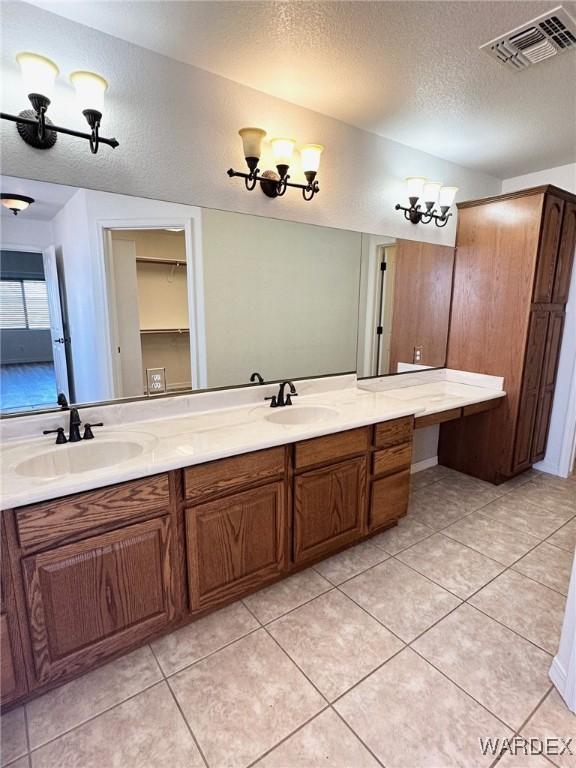 full bathroom with visible vents, a sink, a textured ceiling, and double vanity