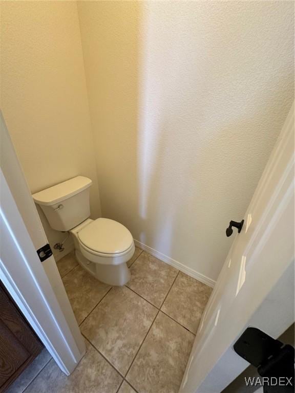 bathroom with tile patterned floors, baseboards, and toilet