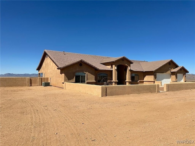 view of front facade with a tiled roof, fence private yard, central AC, and stucco siding