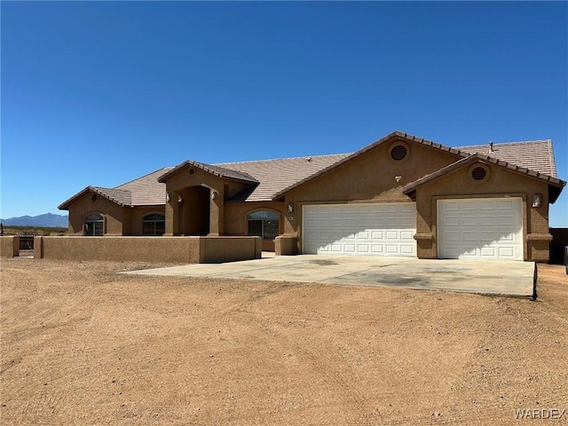 view of front of home featuring concrete driveway, an attached garage, a tile roof, and stucco siding