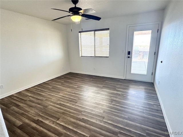 empty room featuring dark wood finished floors, baseboards, and ceiling fan