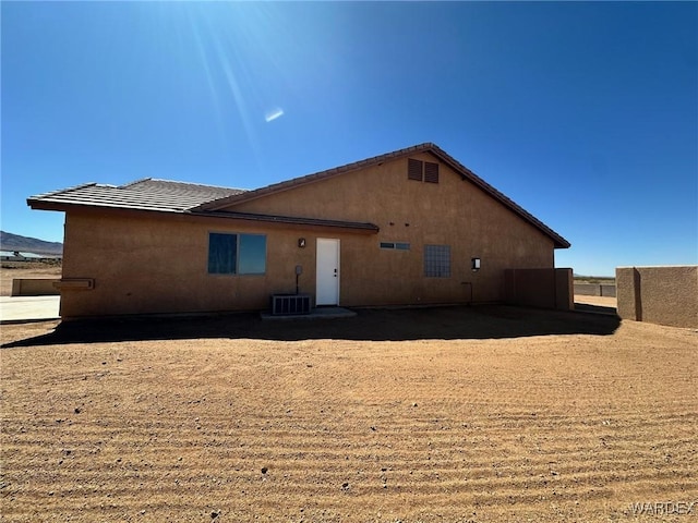 rear view of house featuring stucco siding and a tiled roof