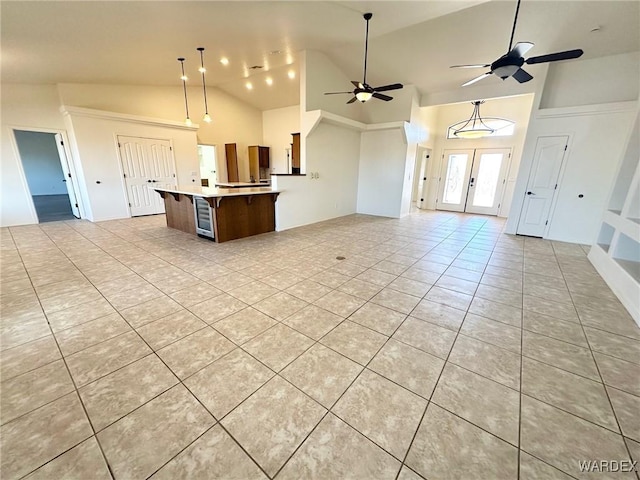 kitchen with open floor plan, a ceiling fan, light tile patterned floors, a center island, and high vaulted ceiling