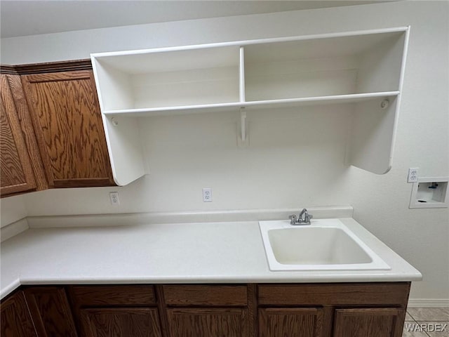 washroom featuring cabinet space, hookup for a washing machine, light tile patterned floors, and a sink