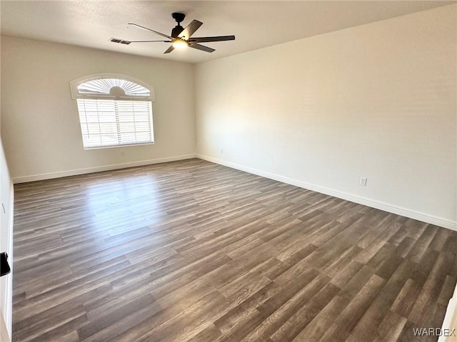 empty room featuring visible vents, a ceiling fan, baseboards, and dark wood-style flooring