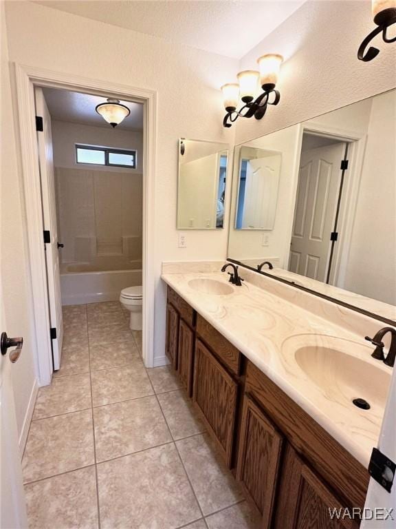 bathroom with tile patterned flooring, double vanity, toilet, and a sink