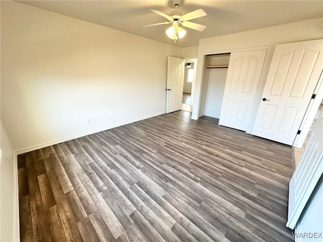 unfurnished bedroom featuring baseboards, a closet, and dark wood-style floors