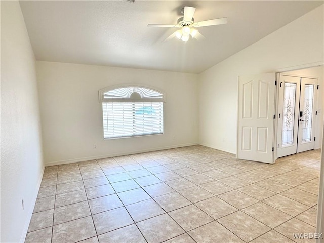 empty room with vaulted ceiling, baseboards, ceiling fan, and light tile patterned floors