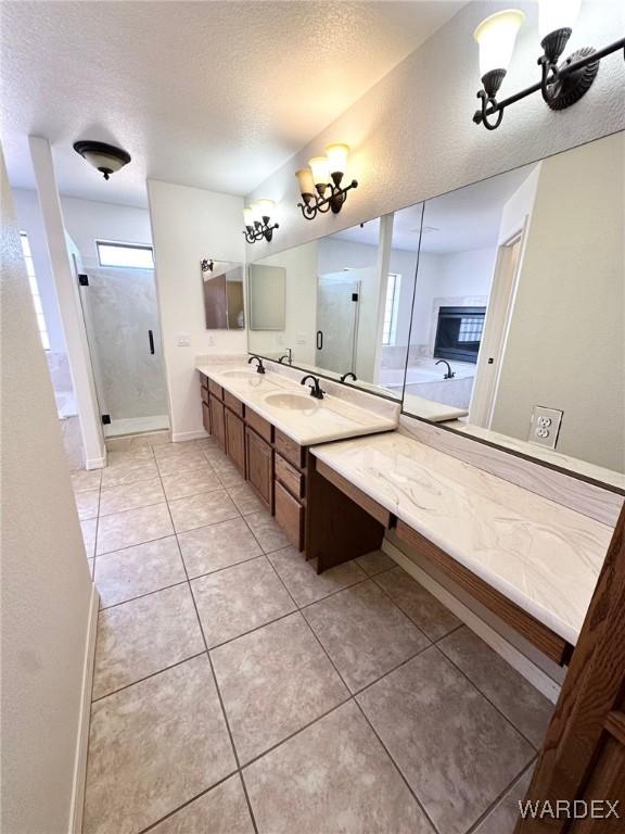 full bath featuring a shower stall, a textured ceiling, tile patterned floors, and a sink