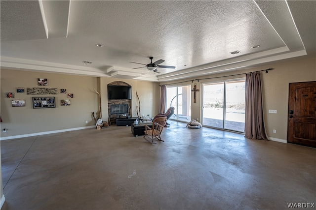 unfurnished living room featuring a fireplace, a raised ceiling, visible vents, a textured ceiling, and baseboards