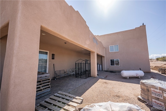 rear view of house with a patio area, fence, and stucco siding