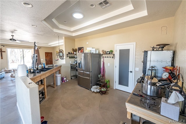 kitchen with stainless steel fridge, visible vents, a tray ceiling, a textured ceiling, and concrete floors