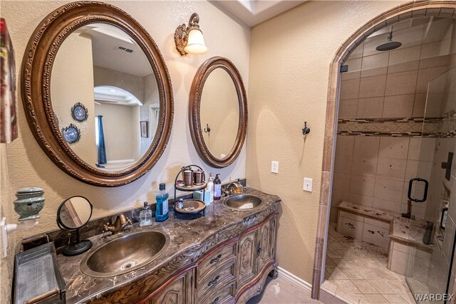 full bath featuring a textured wall, a sink, visible vents, and a shower stall