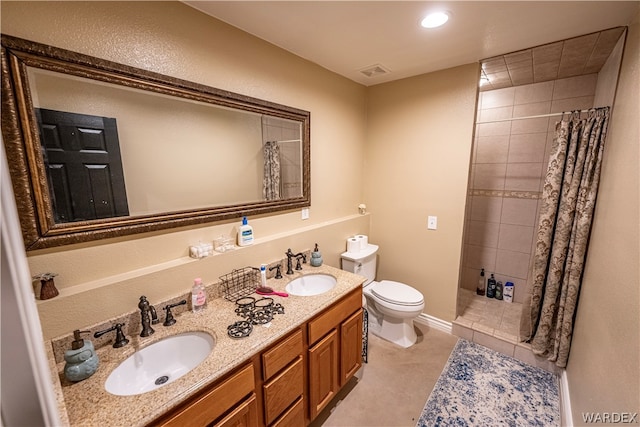 bathroom featuring double vanity, visible vents, a sink, and tiled shower