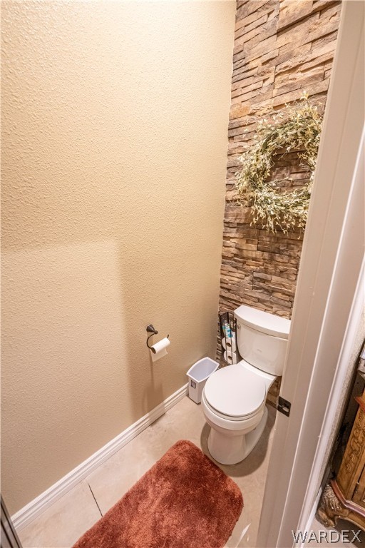 bathroom with toilet, tile patterned flooring, and baseboards