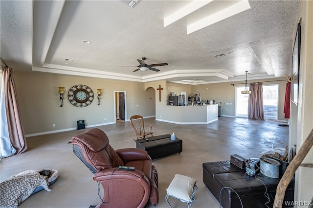 living area with finished concrete flooring, arched walkways, baseboards, a raised ceiling, and a textured ceiling