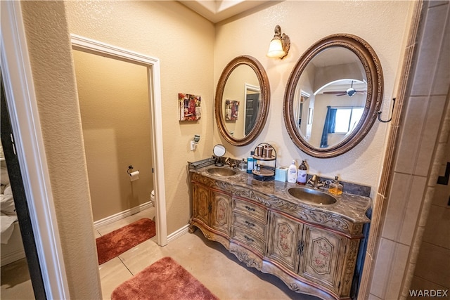 bathroom with baseboards, a sink, toilet, and double vanity