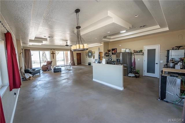 kitchen featuring a raised ceiling, open floor plan, decorative light fixtures, finished concrete floors, and stainless steel refrigerator with ice dispenser