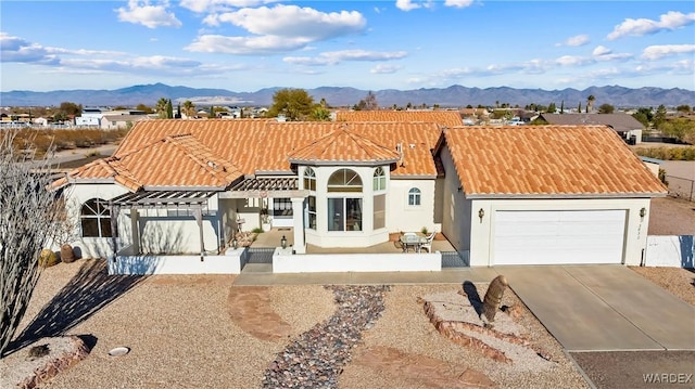 view of front of property featuring an attached garage, a tile roof, a mountain view, and stucco siding