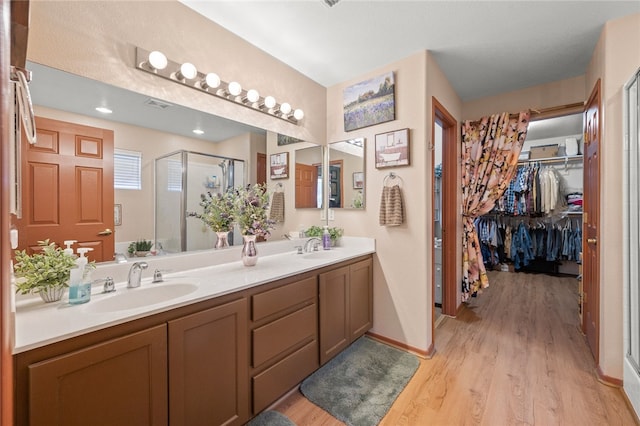 3854 Heather Ave, Kingman, AZ 86401 - bathroom with double vanity, a stall shower, wood finished floors, a spacious closet, and baseboards