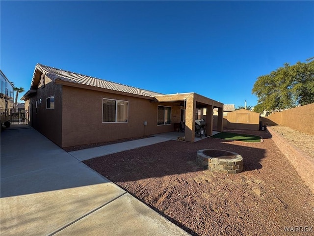 rear view of house featuring a patio, an outdoor fire pit, a fenced backyard, and stucco siding