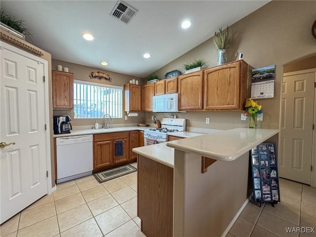 kitchen with light countertops, white appliances, a peninsula, and visible vents