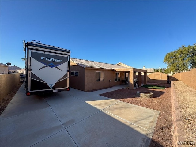 view of front of house featuring a fenced backyard, a tiled roof, a patio, and stucco siding