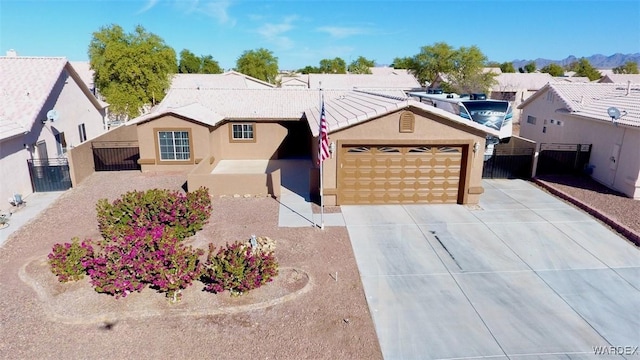 ranch-style house featuring a garage, fence, a tile roof, concrete driveway, and stucco siding