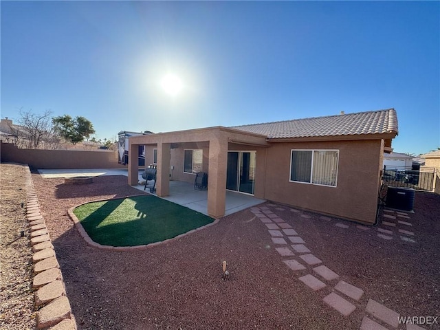 back of property with a tiled roof, a patio area, fence private yard, and stucco siding