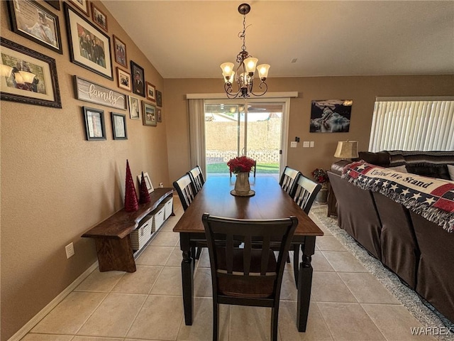 dining room featuring lofted ceiling, a notable chandelier, baseboards, and light tile patterned floors