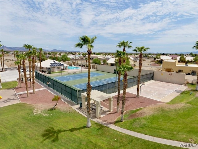 view of tennis court with fence and a yard