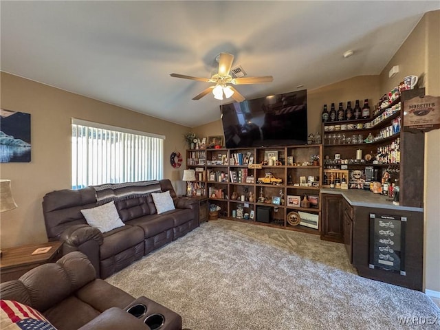 living area featuring vaulted ceiling, ceiling fan, a dry bar, and light carpet