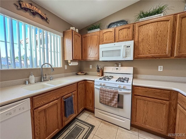 kitchen with white appliances, light tile patterned floors, light countertops, and a sink