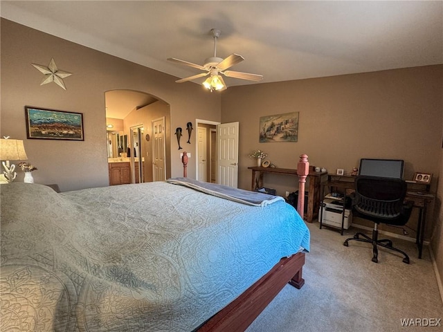 bedroom featuring carpet floors, arched walkways, ensuite bathroom, a ceiling fan, and vaulted ceiling