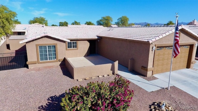 ranch-style house featuring a garage, a tiled roof, and stucco siding