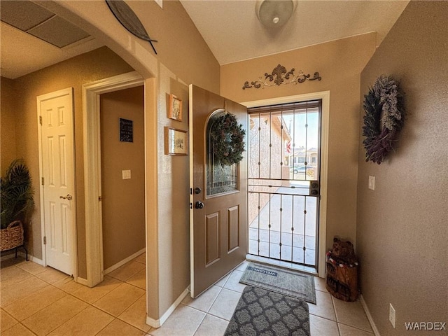 entrance foyer featuring arched walkways, light tile patterned flooring, and baseboards