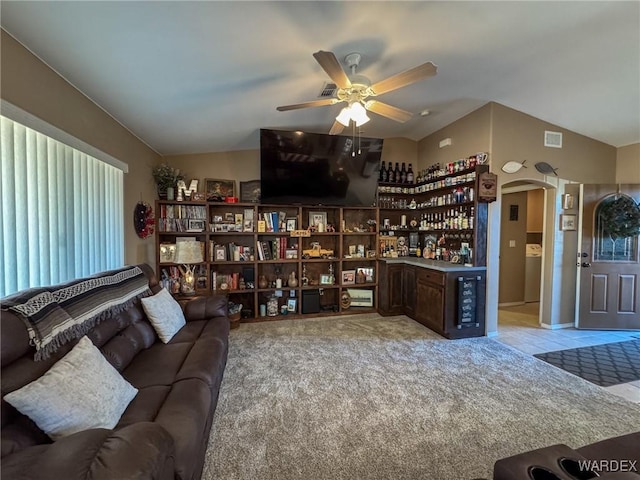 living area featuring arched walkways, light colored carpet, vaulted ceiling, ceiling fan, and a bar