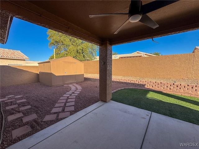 view of patio / terrace with a shed, a fenced backyard, a ceiling fan, and an outbuilding